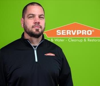 man in SERVPRO gear smiling with a green backdrop 